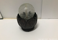 Photo of a decorative tabletop water fountain with a crackled glass orb on a dark brown ornamental base.