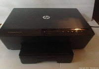 Front view of black HP 6230 inkjet printer with paper output tray extended, showing control buttons on the right side.