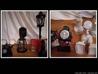 Photo showing assorted black and white outdoor light fixtures including a black lamp post style lantern, wall lanterns, spotlight fixtures, and several white motion sensor floodlights and other white fixtures.