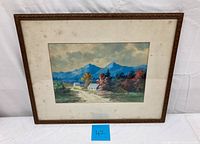 Full view of framed watercolor painting showing countryside landscape with houses, trees, and mountains.