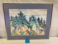 Full view of the colorful landscape watercolor painting showing trees and rocks in multiple colors, framed with blue mat and gold trim.