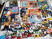 Overhead view of entire lot showing die-cast cars at bottom, carded figures left and center, loose figures at right