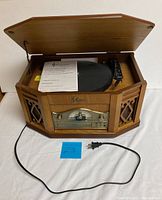Full view of Emerson NR303TT wooden cabinet radio and record player with lid open, turntable visible, power cord out front.