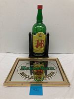 Full image showing large J&B whiskey bottle and Heineken beer mirror framed in gold.