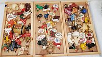 Three wooden trays filled with a variety of vintage liquor bottle stoppers from different brands, laid out for display.