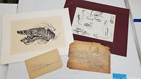 Four pressed paper drawings arranged on a white surface showing subject variety and condition.