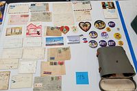 Overview of assorted vintage mail correspondence, playing cards, heart-shaped cards, political pins and binoculars on display.
