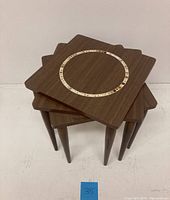 Stacked view showing the tops and legs of the three tables with the mosaic inlaid circular design