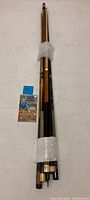 Eight pool cues bundled together resting on a white surface with a billiards guide pamphlet