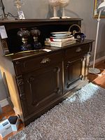 Front and side view of antique wood hutch showing drawers and cupboard doors, marks and scratches visible on wood surface, top decorative backboard visible with items not included.
