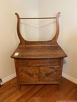 Front view of oak washstand showing full-width drawer, cabinet doors and towel holder