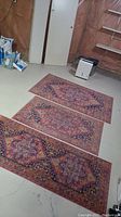 Photo showing three Bodrum rugs laid out on the floor from a diagonal angle: a long runner and two smaller area rugs.