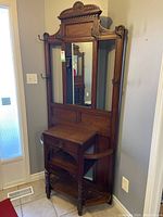 Full front view of carved oak hall tree showing mirror, drawer and umbrella holders