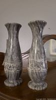 Pair of gray and white marbled stone vases with flared tops and engraved decorative bands.