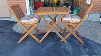 Photo of entire veranda set showing table with two folding chairs and cushions.
