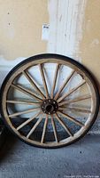 Front view of the antique wooden wagon wheel showing full circular frame with metal rim and wood spokes.