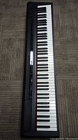 Full length top view of one electronic keyboard with black and white piano keys and control panel left side.