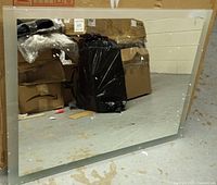 Unboxed rectangular LED mirror leaning against wall, silver frame visible