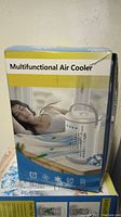 Photo of the product packaging showing a woman resting near the air cooler with the product name 'Multifunctional Air Cooler' and some icons.