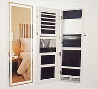 Front view of white wooden jewelry armoire with the door open, showing full-length lighted mirror and multiple black-lined organizer panels for jewelry storage inside.