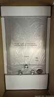 Front view of the gas water heater in original box with styrofoam supports