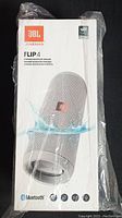 Front view of factory-sealed box showing JBL Flip 4 speaker image and branding, sealed in plastic wrap