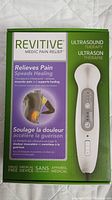 Front view of sealed factory box for Revitive Medic Pain Relief ultrasound therapy device showing device image and pain relief claims in English and French.