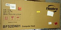 Box labeled 'Hoobro Computer Desk BF52DN01', listing net weight, gross weight, and dimensions, indicating factory sealed packaging.