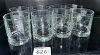 Set of six clear cylindrical bar glasses with thick bases arranged in two rows.