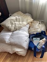 Overview of all items in the lot: down comforter, fleece blanket, bed linens, towels, and tote bag with drink stirrers and straws.