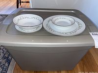 Plastic bin lid with two plates and two bowls displayed to show china pattern and condition