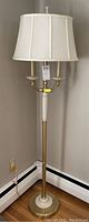 Full view of the lamp showing the white fabric lampshade and metal and ceramic stand.
