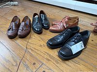 Four pairs of men's dress shoes in size 10.5 displayed on wooden floor, viewed from above and side, showing details of style and condition.