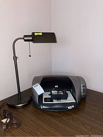 HP Deskjet 5550 printer and adjustable bronze desk lamp seen on wood surface. Lamp cord visible unplugged.