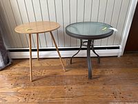 Side view of two side tables, wooden table on the left and metal glass-top table on the right.