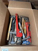 Box of assorted hand tools including pipe wrenches, hammers, mallets, scissors and pliers