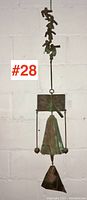 Full-length view of bronze wind chime showing top book element, central bell, striker and hanging loop