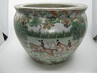 Front view of the flower pot showing the hunting scene and decorative leaves near the rim.