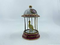 Front side view of Limoges porcelain birdcage with gold trim and porcelain bird inside.
