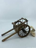 Side view of the wooden Red River cart model showing the wheels and shafts with informational tag attached.