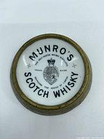 Top view of the front of the dish showing Munro's Scotch Whisky lettering and crest emblem with brass rim.
