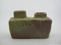 Front view of vintage rectangular pottery vase with two cylindrical openings and mottled glaze finish showing reddish and green hues.