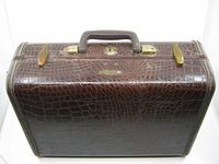 Front angled view of the dark brown faux crocodile Samsonite train case showing brass clasps, handle, and textured exterior surface.
