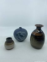 Three handmade miniature pottery vases in different shapes and colors against a white background.