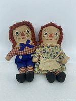 Front view of Raggedy Ann and Andy dolls showing facial features, clothing, and general condition