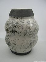 Front view of vintage Raku pottery vase showing crackled white and black glaze with bulbous shape and matte black top and bottom edges.
