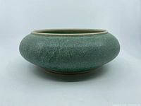 Side view of green speckled studio pottery bowl showing shape and glaze texture