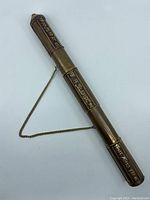 Top view of vintage cylindrical metal Tibetan or Chinese scroll/incense case with visible raised script and attached chain.