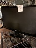 Front view of the Acer 24-inch LED monitor on a metal shelf, showing the screen and base stand with the Acer logo.