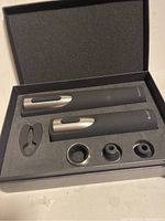 Wide shot of the electric wine openers, foil cutter, and accessories in foam insert box.